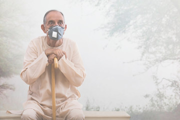 Senior man sitting outside wearing a pollution mask. (Health and fitness) 