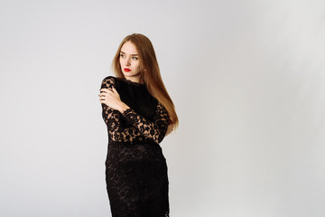 Sexy beautiful pensive girl in a black lace dress in the studio. Beautiful lady on a white background