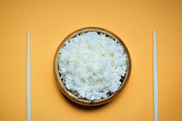 Bol lleno de arroz blanco hervido, acompañado de largos palillos