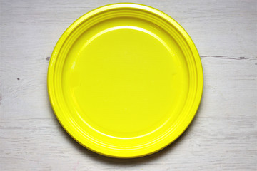 Plato circular amarillo, sobre mesa de madera