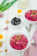 Salad of boiled beet. Beetroot salad with prunes, walnuts, eggs and sour cream in a bowl on white background. Healthy food. Vertical orientation.