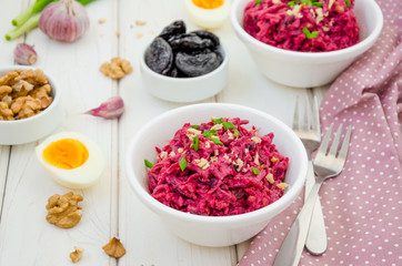 Salad of boiled beet. Beetroot salad with prunes, walnuts, eggs and sour cream in a bowl on white background. Healthy food. Horizontal orientation.