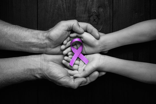 Hands holding purple ribbons world cancer day.