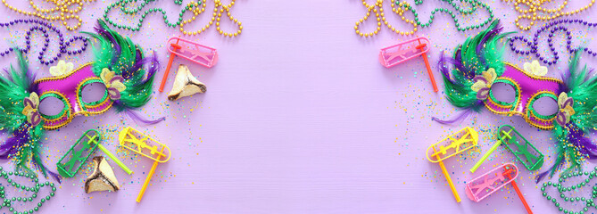 Purim celebration concept (jewish carnival holiday) over purple wooden background. Top view, Flat lay