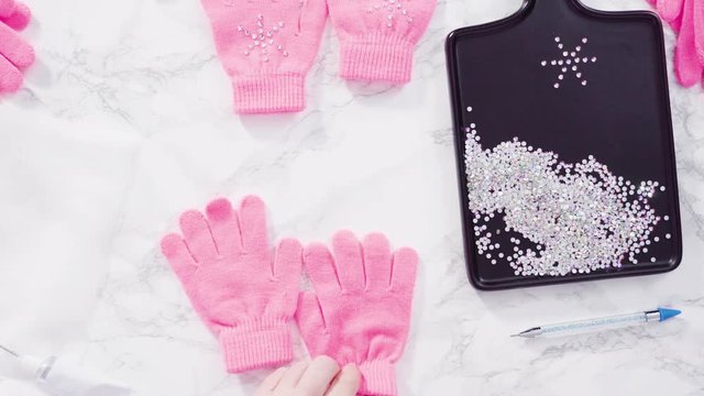 Flat lay. Rhinestone pink kids gloves with snowflake shapes.