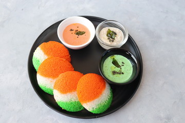 Tiranga Idli or Tricolor Idly cooked in  Indian National Flag colors - saffron or orange, white and green. Served with tiranga chutney. Concept for Indian Independence or Republic day greeting card. 