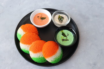 Tiranga Idli or Tricolor Idly cooked in  Indian National Flag colors - saffron or orange, white and green. Served with tiranga chutney. Concept for Indian Independence or Republic day greeting card. 