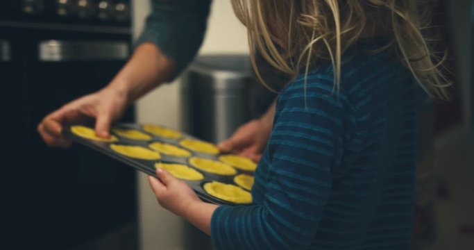 Toddler preparing cookies for the oven with his mother