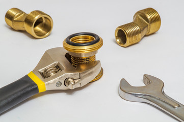 Set of brass fittings and tool is often used for water and gas installations on gray background
