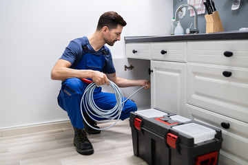 Plumber Cleaning Clogged Sink Pipe