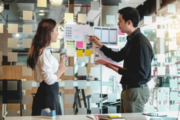 Two Asian application designers work together to brainstorm, outline, and develop mobile applications.