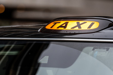 A british london black taxi cab sign with defocused  background