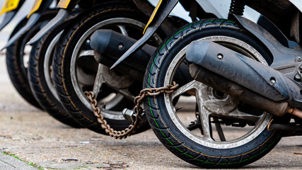Fototapeta premium The rear wheels of the pizza delivery scooter chain are locked with an anti-theft chain