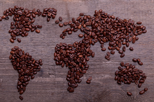 Dramatic photo of world map made of arabic roasted coffee beans on old vintage wooden table.