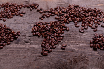 Dramatic photo of world map made of arabic roasted coffee beans on old vintage wooden table.