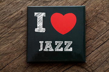 I Love Jazz written on black note with wood background