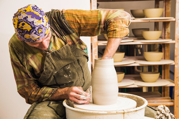 Portrait of the potter artist making clay bowl on the potter's wheel. Creating pottery art and...