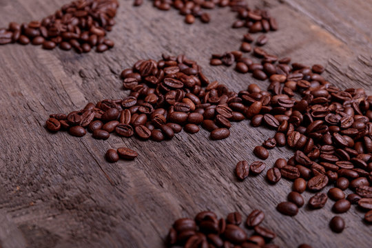 Dramatic photo of world map made of arabic roasted coffee beans on old vintage wooden table.