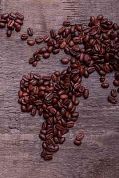 Dramatic photo of world map made of arabic roasted coffee beans on old vintage wooden table.