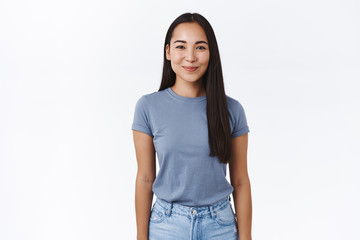 Cheerful, feminine and silly young asian girlfriend smiling happy, look at camera with admiration and joy, standing casual pose with arms down, posing over white background, studio portrait
