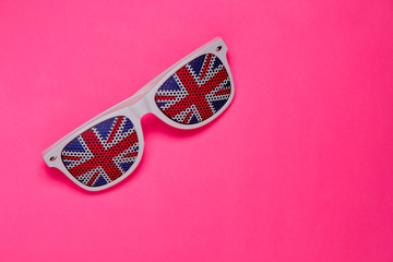 White rimmed sunglasses with UK flag on pink isolated background. Free space for text.