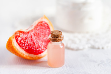 Obraz na płótnie Canvas Concept of natural fruity organic ingredients in cosmetology. Extract of grapefruit for moisturizing, delicate skin nutrition, pore narrowing and anti-cellulite effect. White background, copy space
