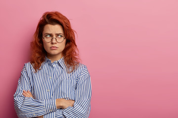 Photo of offended displeased angry woman stands with insulted look and crossed hands, sulks while...