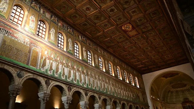 Ravenna, Italy, December 2019. Basilica of Sant'Apollinare Nuovo. Pan movement footage from the apse to the entrance of the magnificent mosaics along the sides of the main nave.