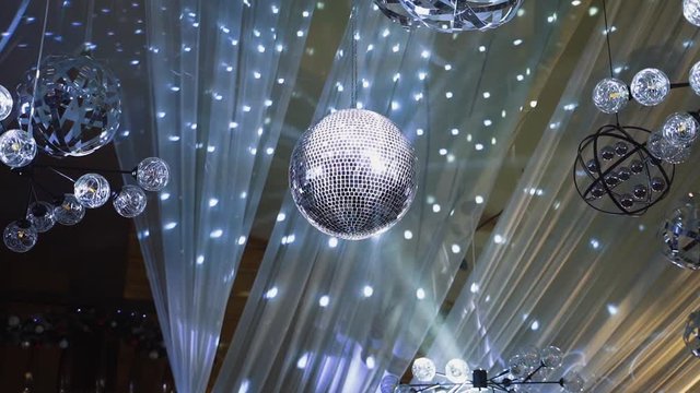 Round ball rotating in the nightclub. Beautiful shining sphere on the ceiling. Disco ball on the background of shimmering lights.
