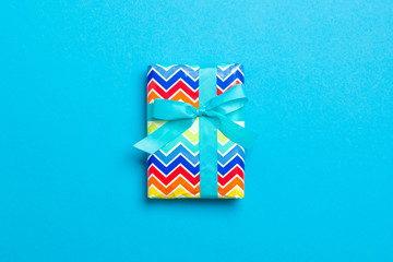 Gift box with blue bow for Christmas or New Year day on blue background, top view with copy space