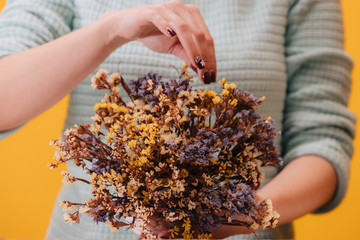 Dried wildflowers. Many tiny blue and yellow flowers in a white vase. Florist girl adjusts the bouquet.