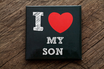 I Love My Son written on black note with wood background