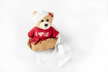 Teddy bear with bandaged head on white background.