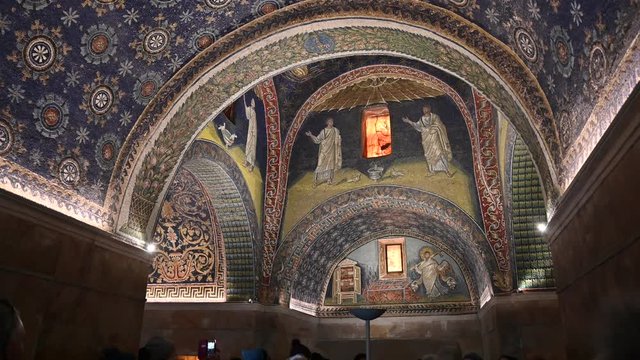 Ravenna, Italy, December 2019. Mausoleum of Galla Placidia, tilt movement upwards at the entrance: people admire the beauty and charm of the place. The blue of the vault recalls a starry night.