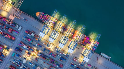 Poster Container ship working at night, Business import export logistic and transportation of International by container ship in the open sea, Aerial view. © Kalyakan