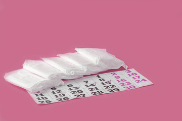 Protective menstrual pads and calendar of menstruation cycle (period) on pink background. The concept of women gynecological health and intimate hygiene. Flat lay, copy space for text.
