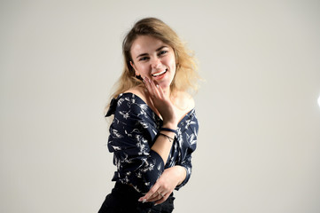Fototapeta premium Concept woman in a dark shirt smiles and talks. Photo Portrait of a girl model with excellent makeup with good teeth in the studio on a white background.