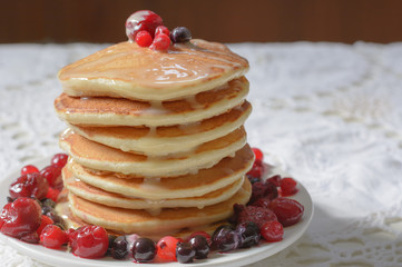 Homemade pancakes with berries and  condensed milk on white plate isolated