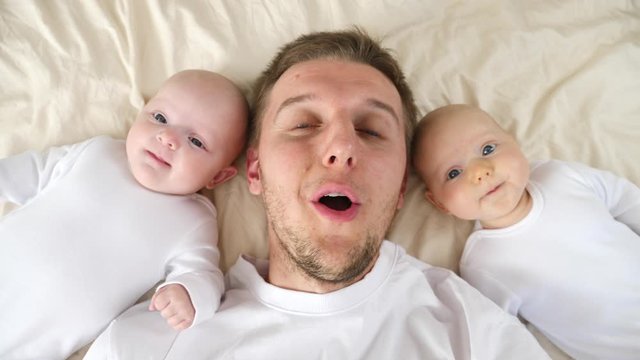 Happy Young Father With Twin Babies.