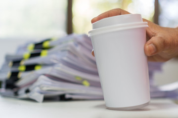 Businessman holding white Paper coffee cup mock-up for logo with document paperwork on meeting....