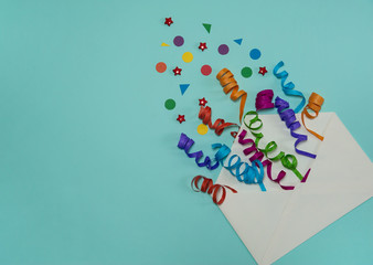 The concept of birthday. Paper ribbons, confetti, and stars fly out of an open envelope on a light blue background. Free space.