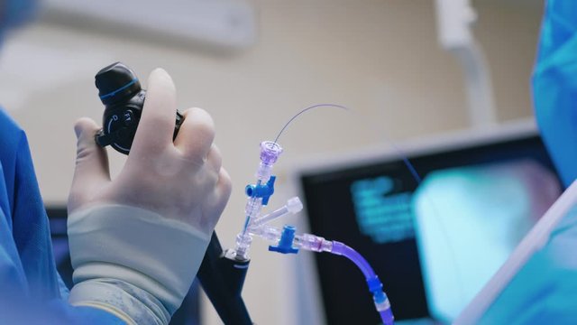 Endoscopic surgery. Surgeon's hand holds medical instrument on the blur background of a monitor. Close-up.