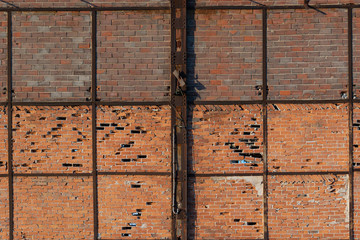 Old brick wall with holes and rusted metal beams
