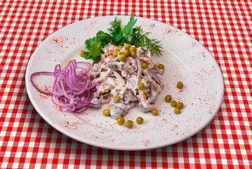 Traditional Russian salad Olivier decorated with onion and green vegetables