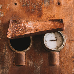 Round gauge meter on rusted machine
