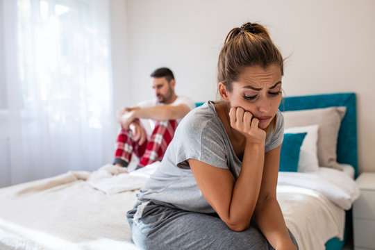 Image of Sad unhappy couple having problem in bed. Troubled woman expressing despair. Relationship Difficulties: Young couple having problems. Moody yong woman sitting at home