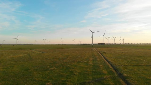 Windmill - wind power plant turbines on green fields at sunset during summer European Union, aerial drone shot.