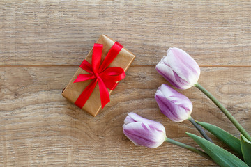Gift box with tulip flower on the wooden background.