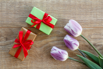 Fototapeta premium Gift boxes with tulip flowers on the wooden background.