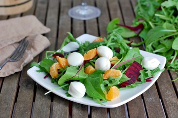 Fresh salad with arugula, lettuce, beetroot, mandarin and mozzarella